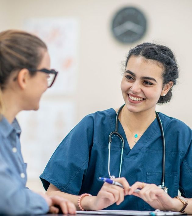 A nurse is smiling while talking to a patient.