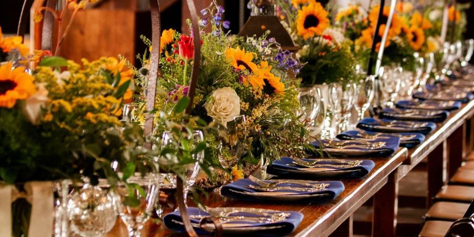 A long table with plates , glasses , and flowers on it.