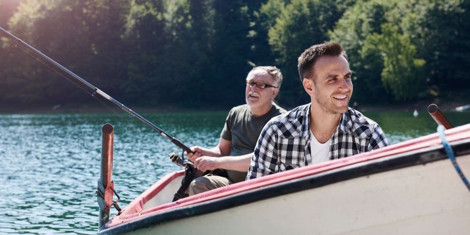 Two men are fishing in a boat on a lake.