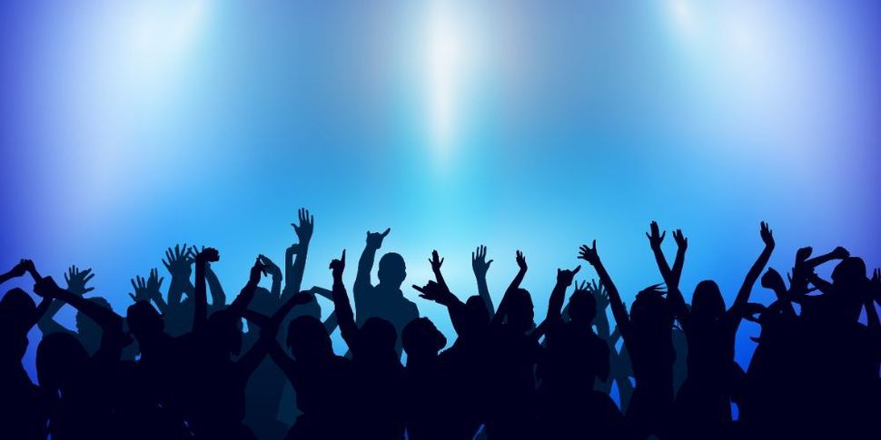 A crowd of people standing in front of a stage with their hands in the air