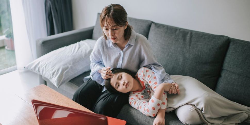 Two women are sitting on a couch looking at a laptop.
