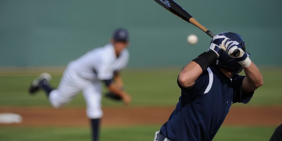 A baseball player is swinging a bat at a ball while a pitcher throws the ball.