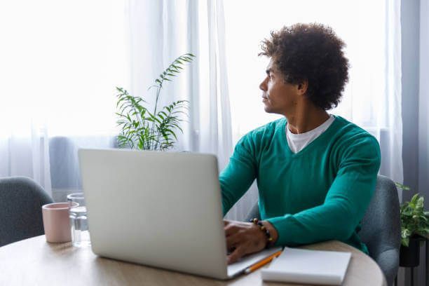 a man is sitting at a table using a laptop computer .