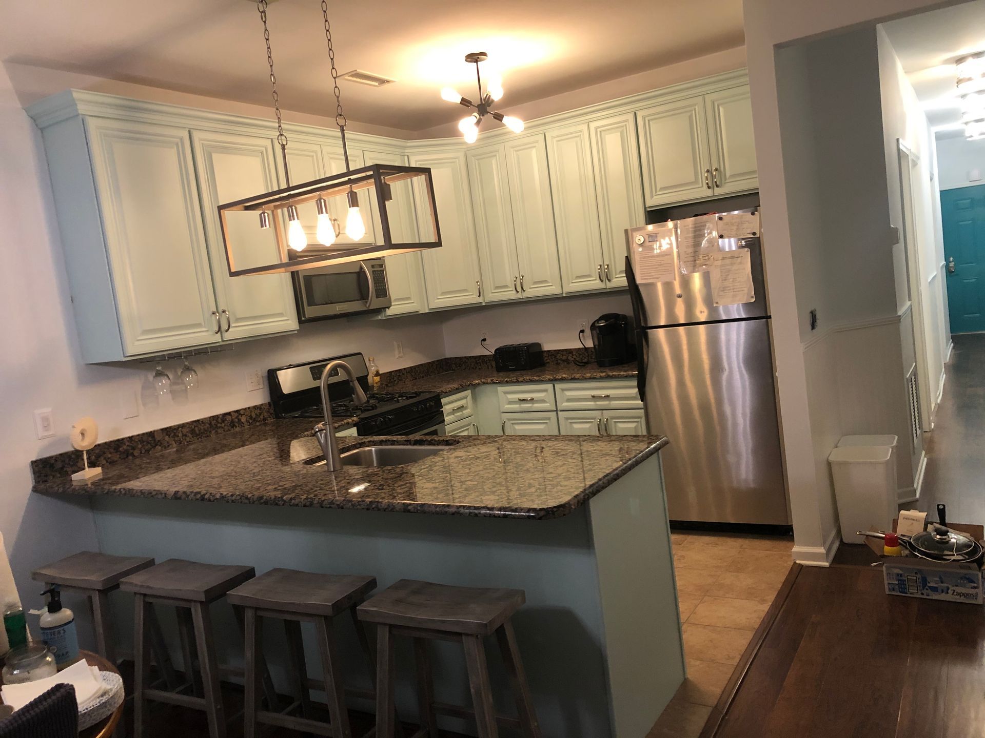 A kitchen with white cabinets , granite counter tops , stainless steel appliances and a stainless steel refrigerator.
