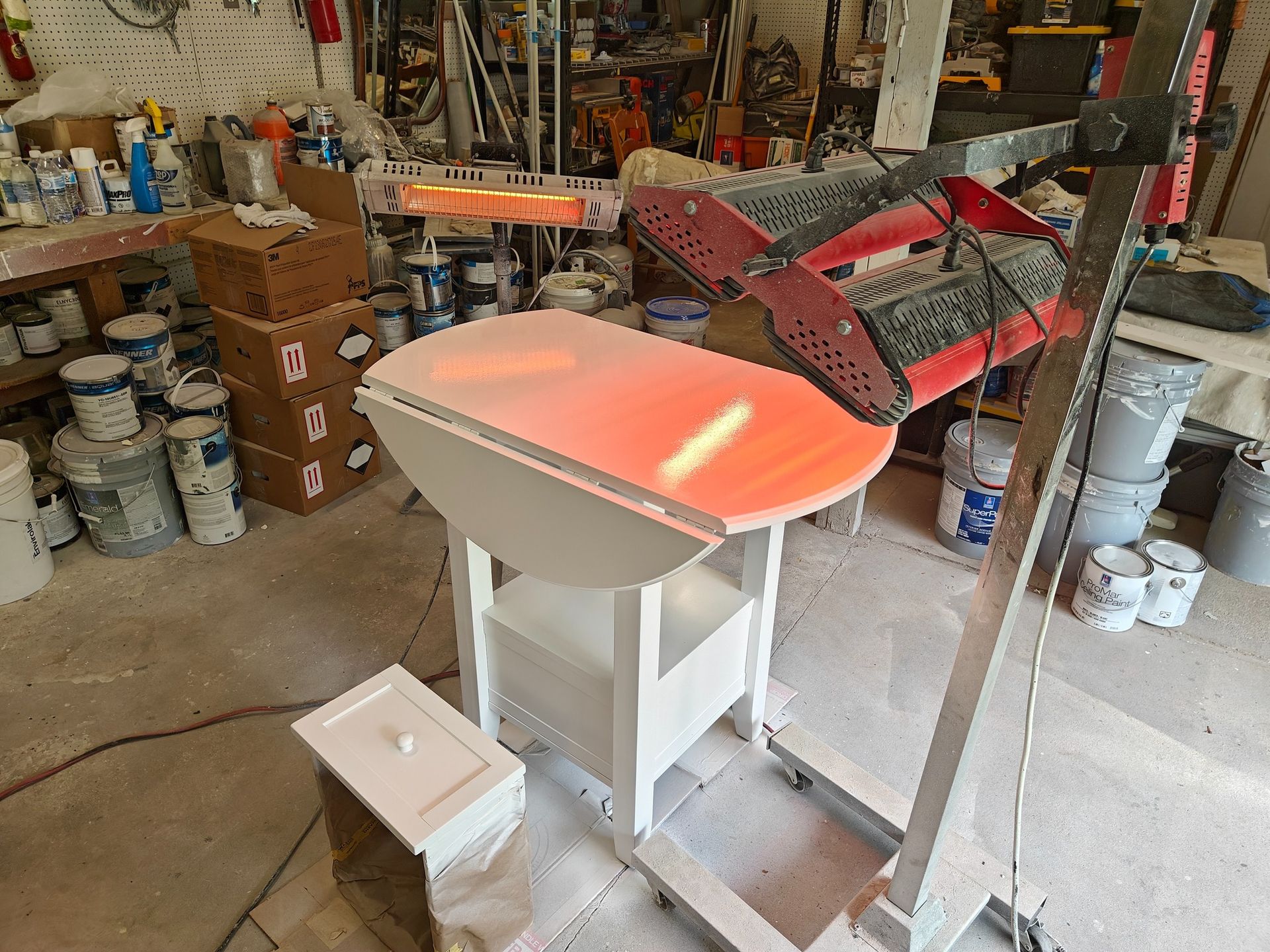 A table with a red top is sitting in a room with paint buckets.