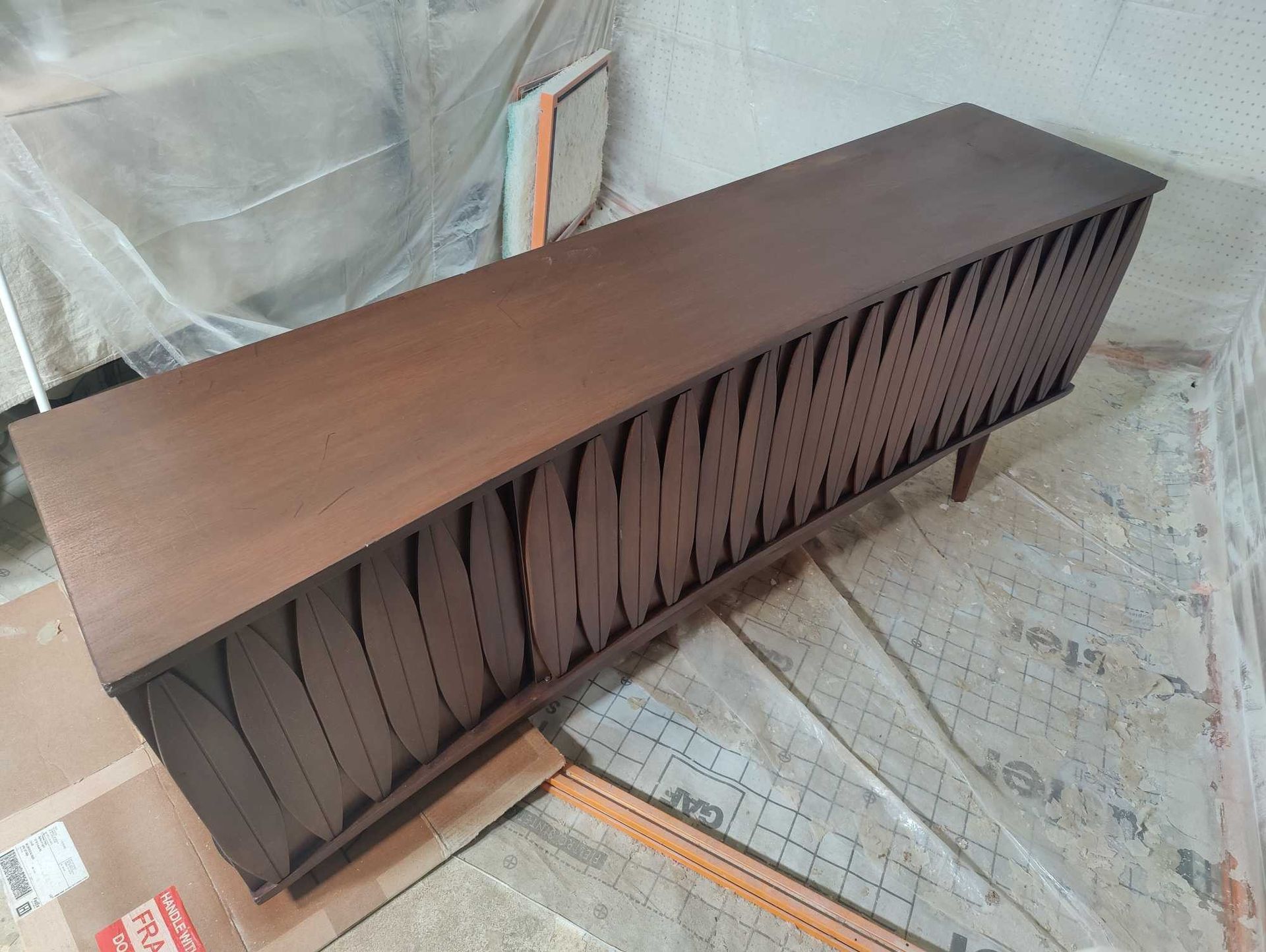 A wooden shelf is sitting on the floor in a room.