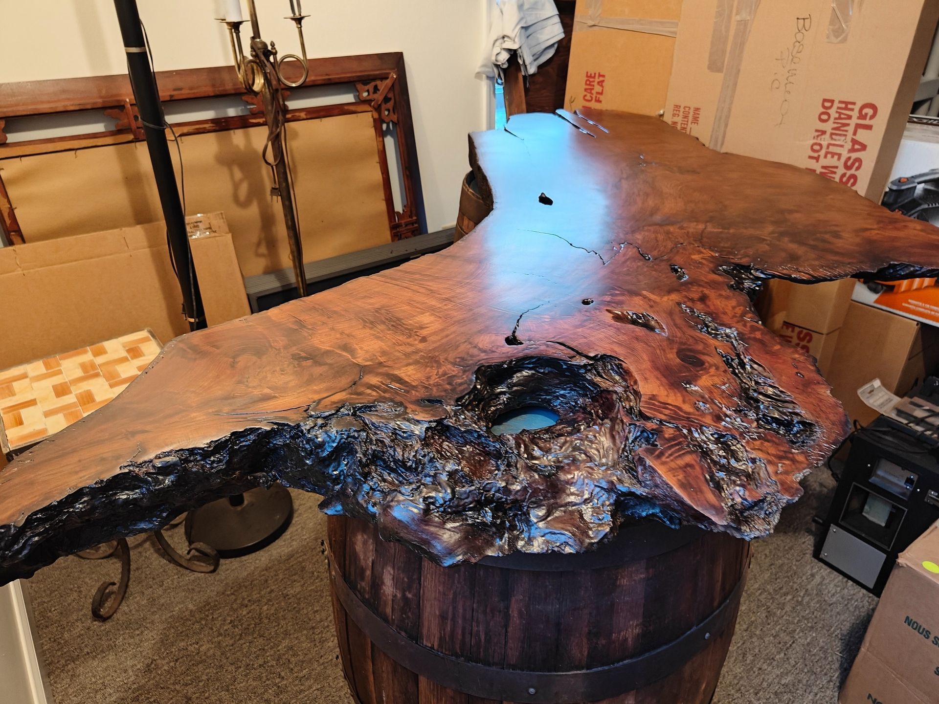 A large piece of wood is sitting on top of a wooden barrel.