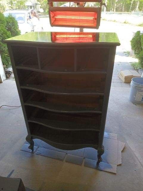 A dresser is sitting on a cardboard box on a porch.