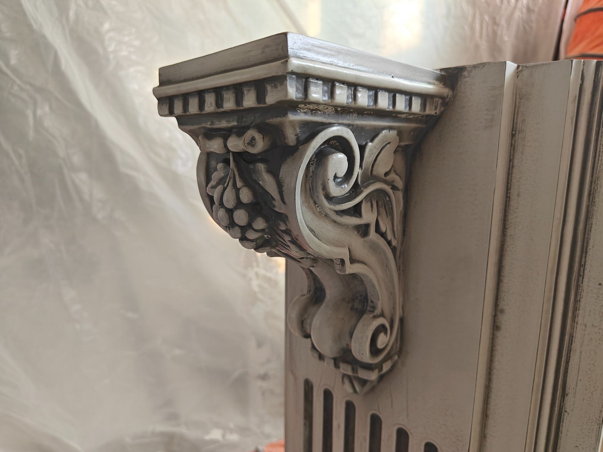 A white wooden shelf with a carved design on it