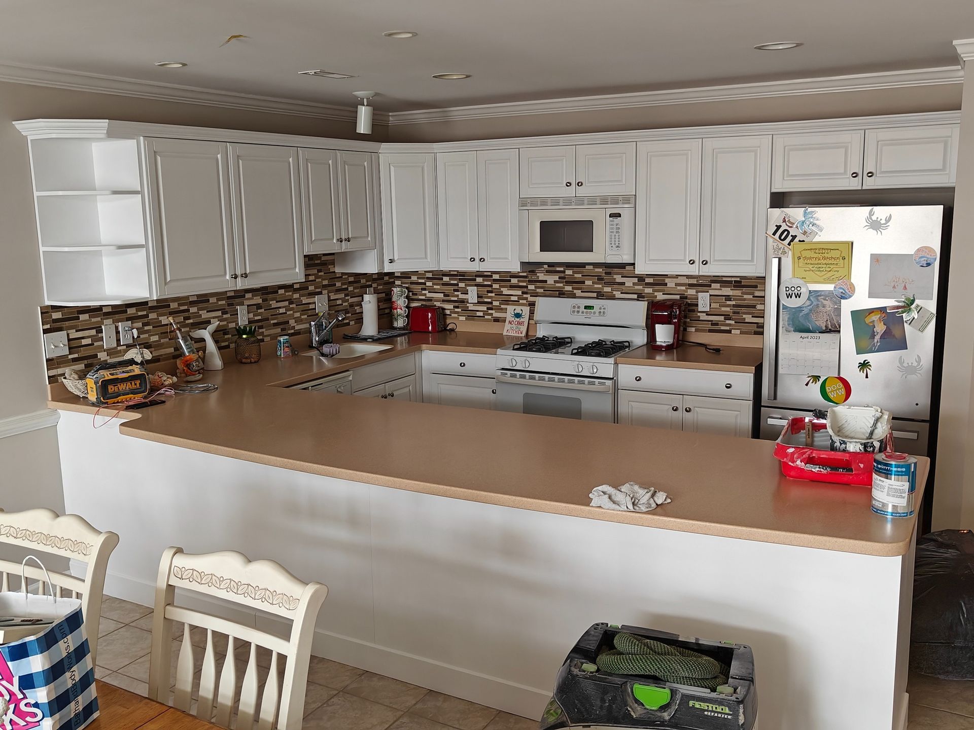 A kitchen with white cabinets , a stove , a refrigerator , and a microwave.