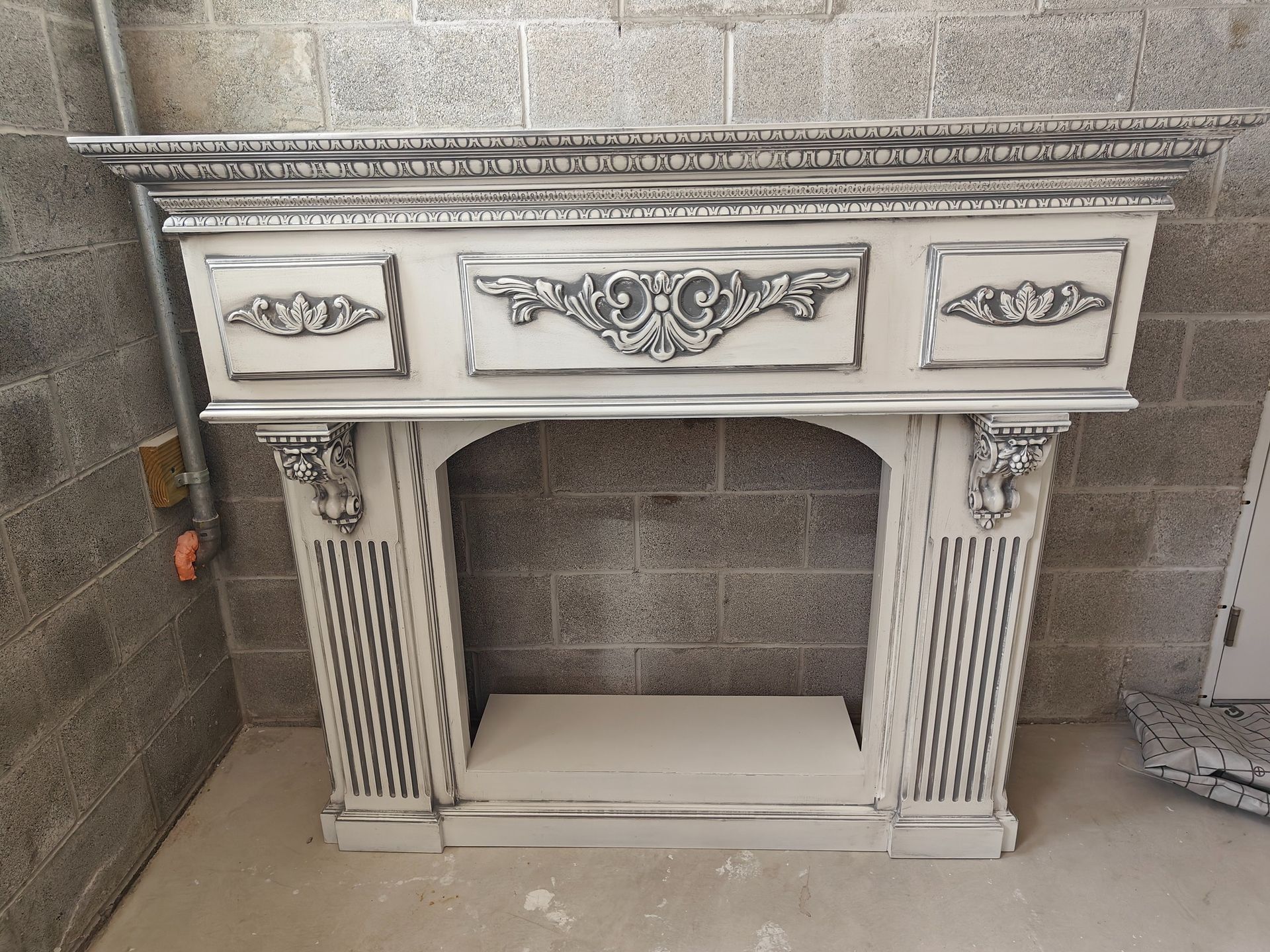 A white fireplace mantle is sitting in front of a brick wall.