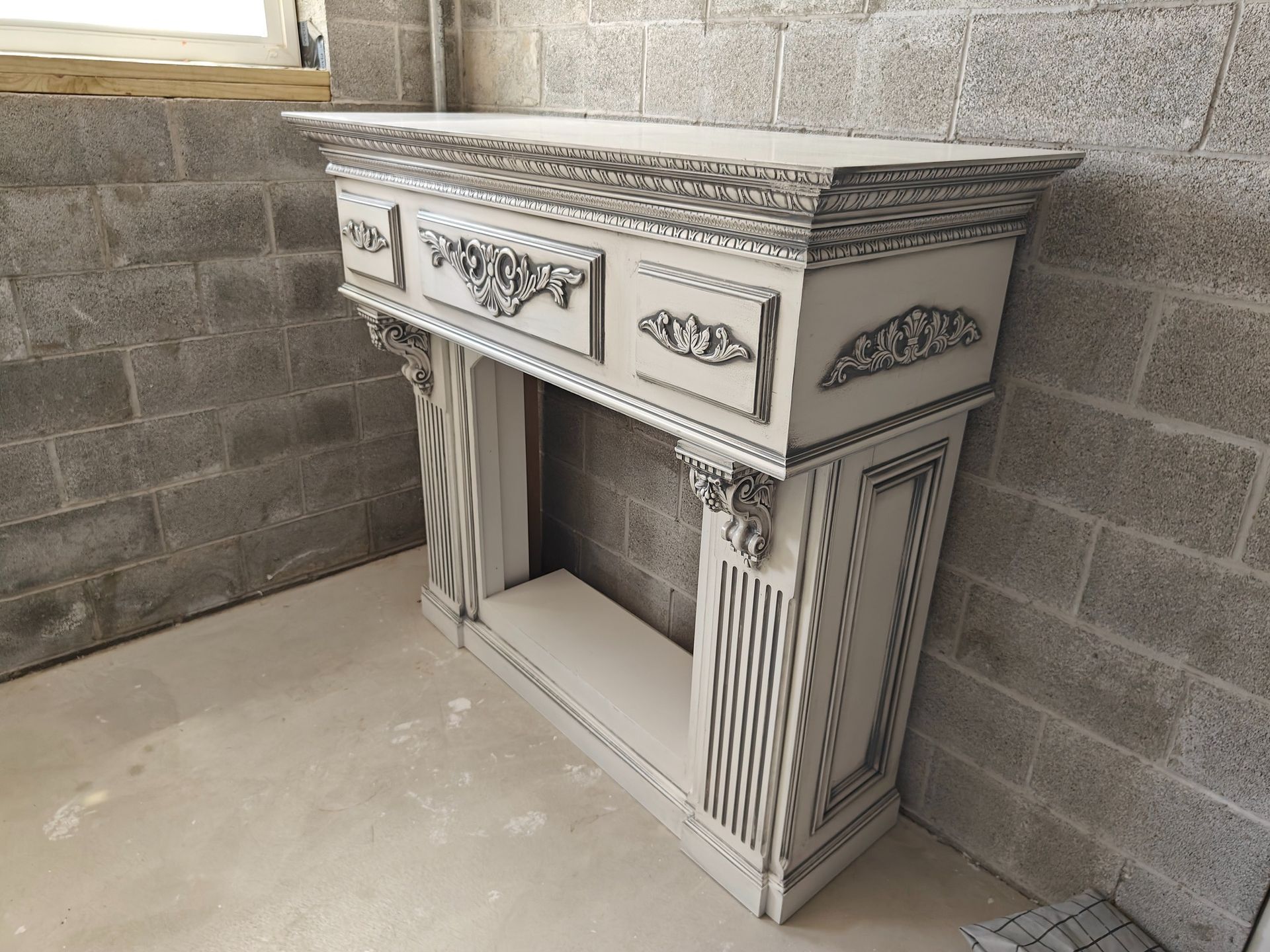 A white fireplace mantle is sitting in front of a brick wall.