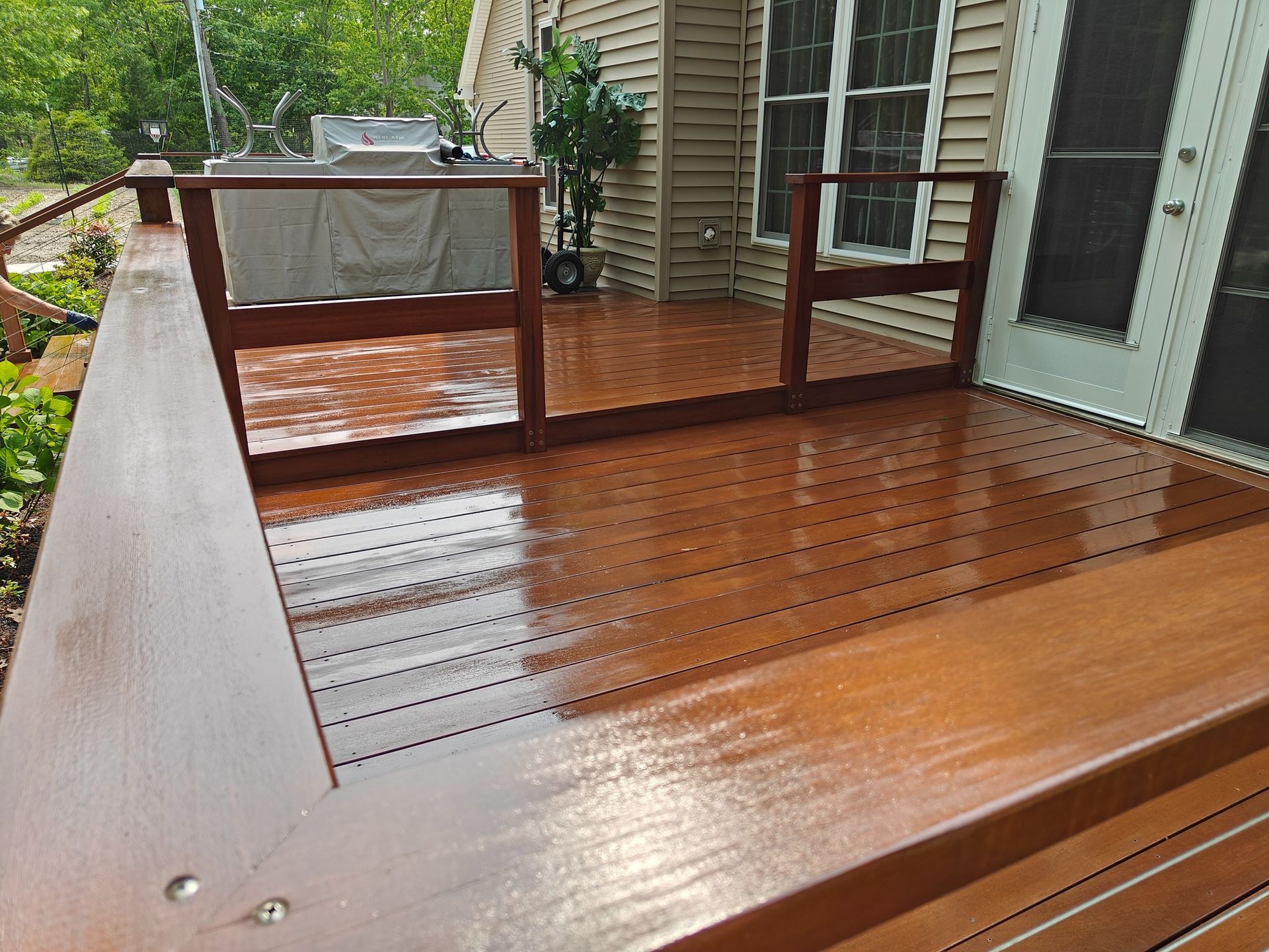 A wooden deck with a fence and stairs in front of a house.