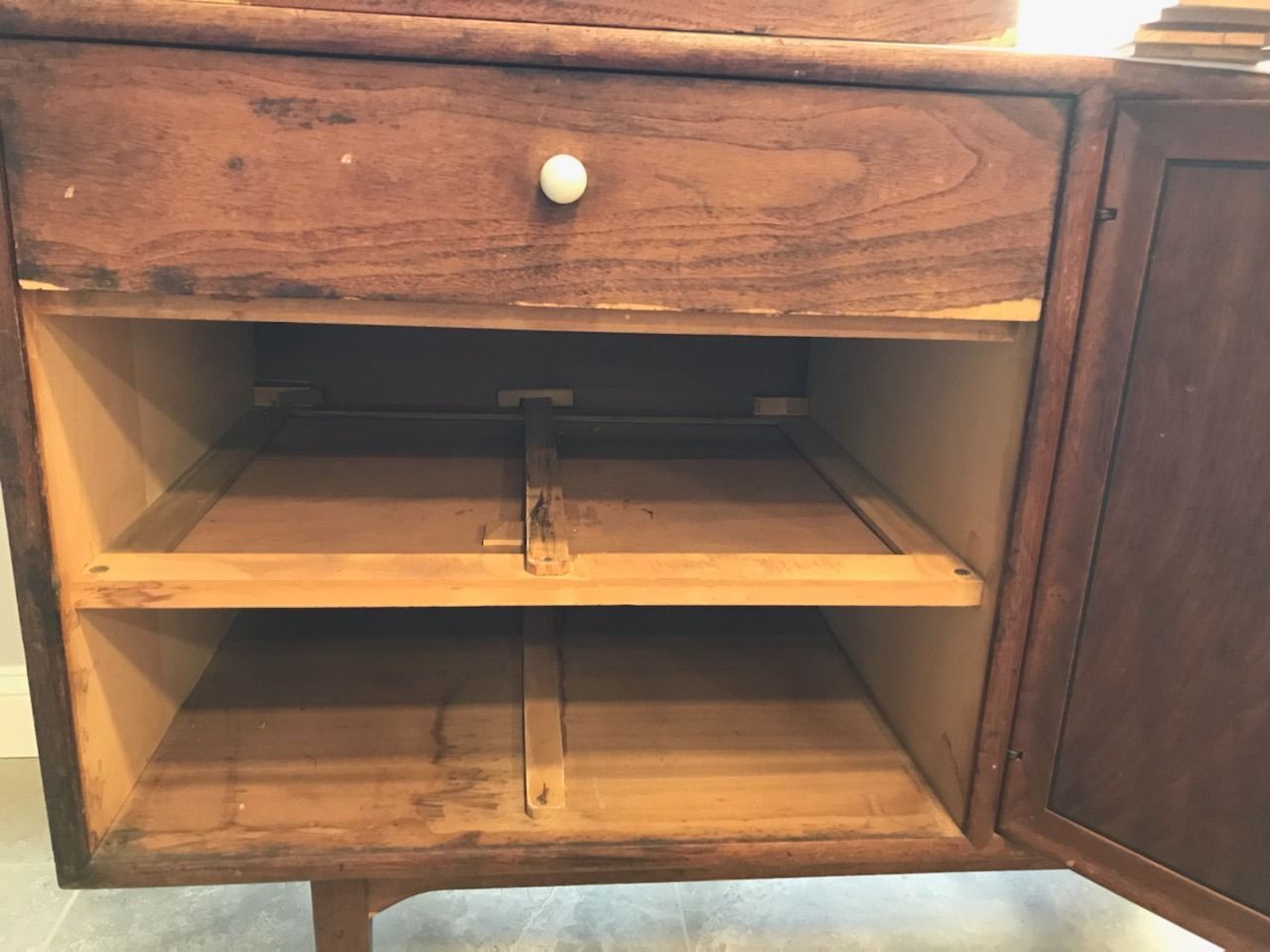 The inside of a wooden cabinet with a drawer and shelves.