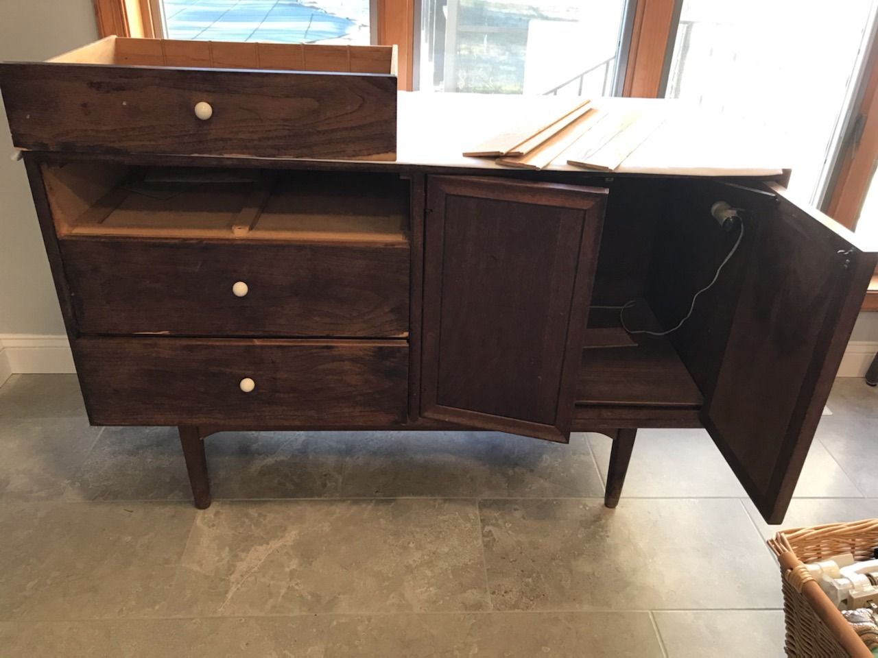 A wooden dresser with the door open and the drawers empty.