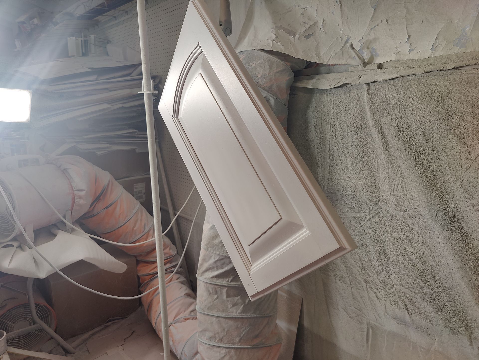 A white door is hanging from the ceiling in a room.