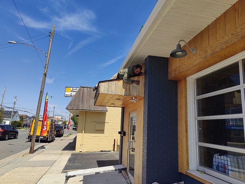 A man is standing under a canopy on the side of a building.