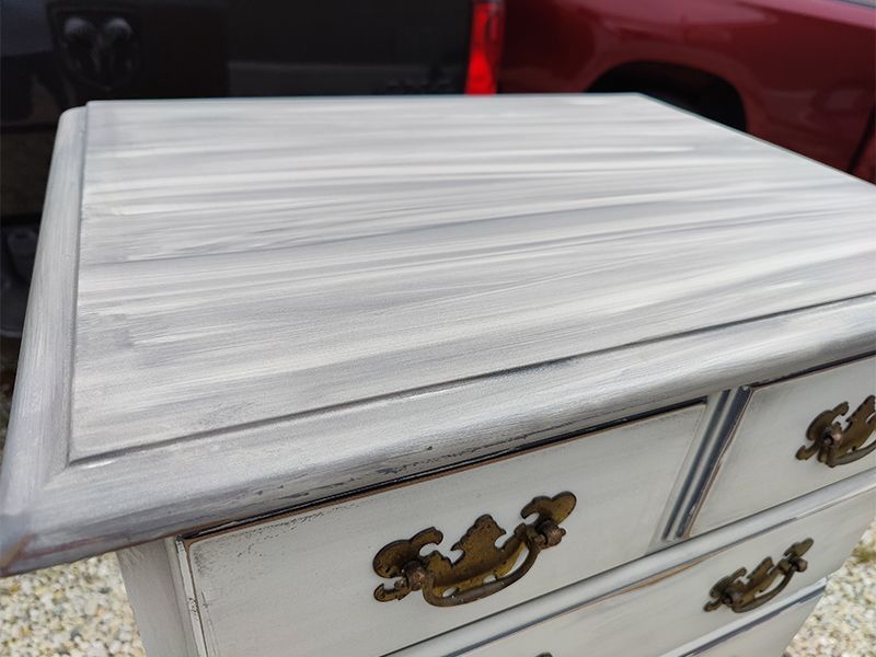 A white dresser with gold handles is sitting in front of a red truck.