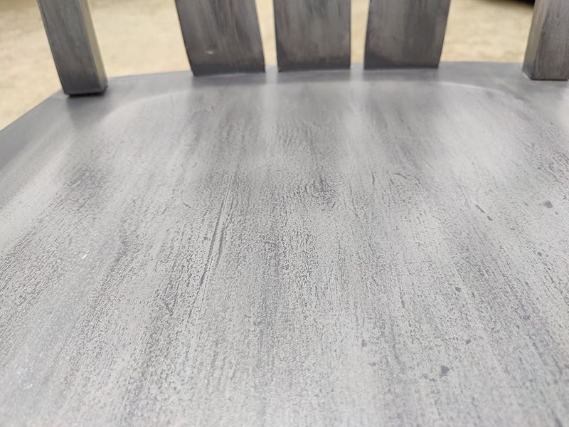 A close up of a gray wooden chair 's seat.