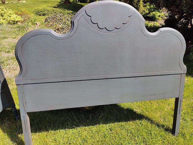 A gray headboard is sitting on top of a lush green field.