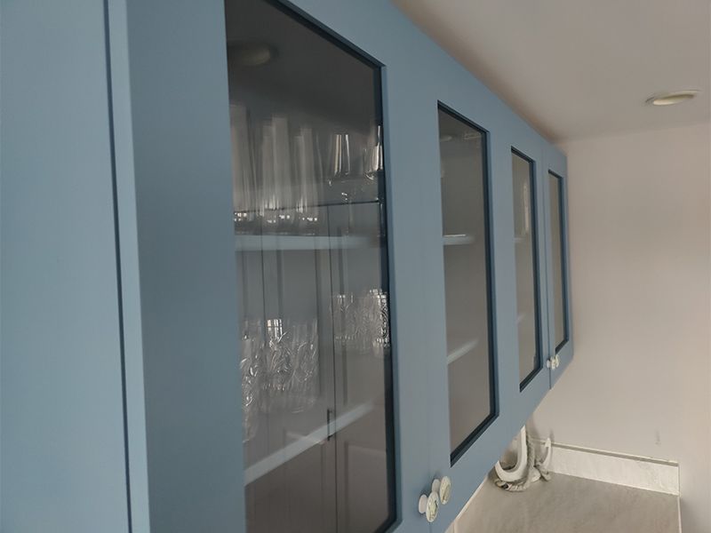A kitchen with blue cabinets and glass doors