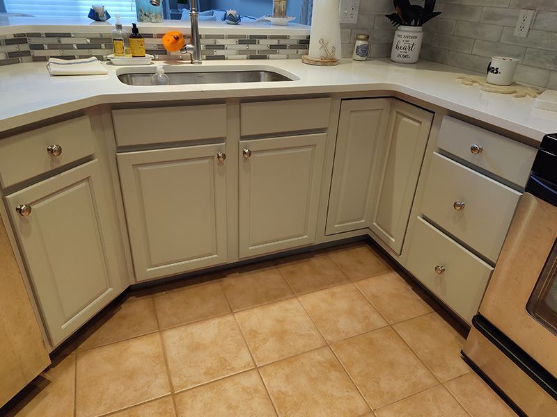 A kitchen with white cabinets , a sink , and a stove.