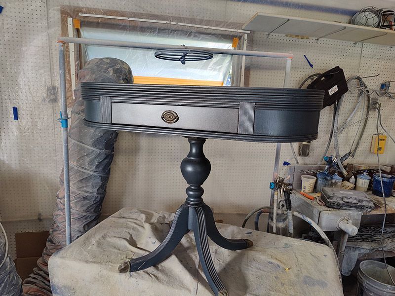 A small table with a drawer is sitting on a table in a garage.