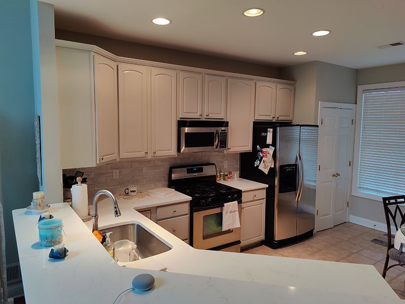 A kitchen with white cabinets , stainless steel appliances , a sink , and a refrigerator.