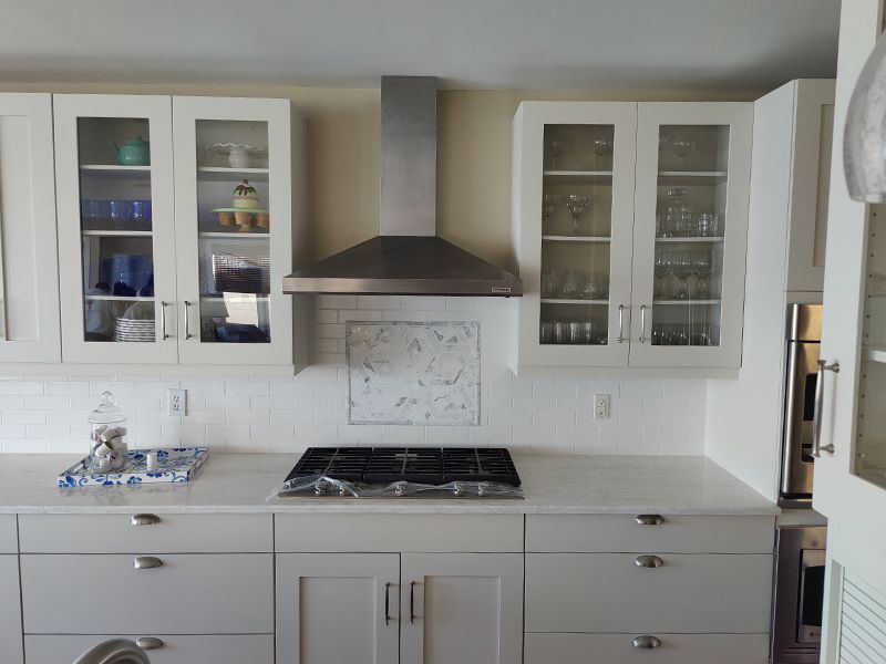 A kitchen with white cabinets and a stove top oven