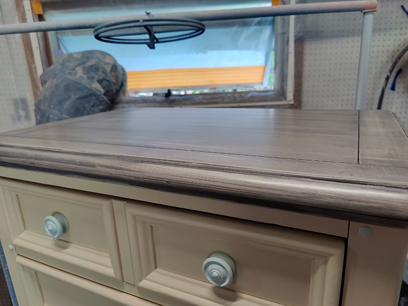 A white dresser with two drawers and a window in the background.