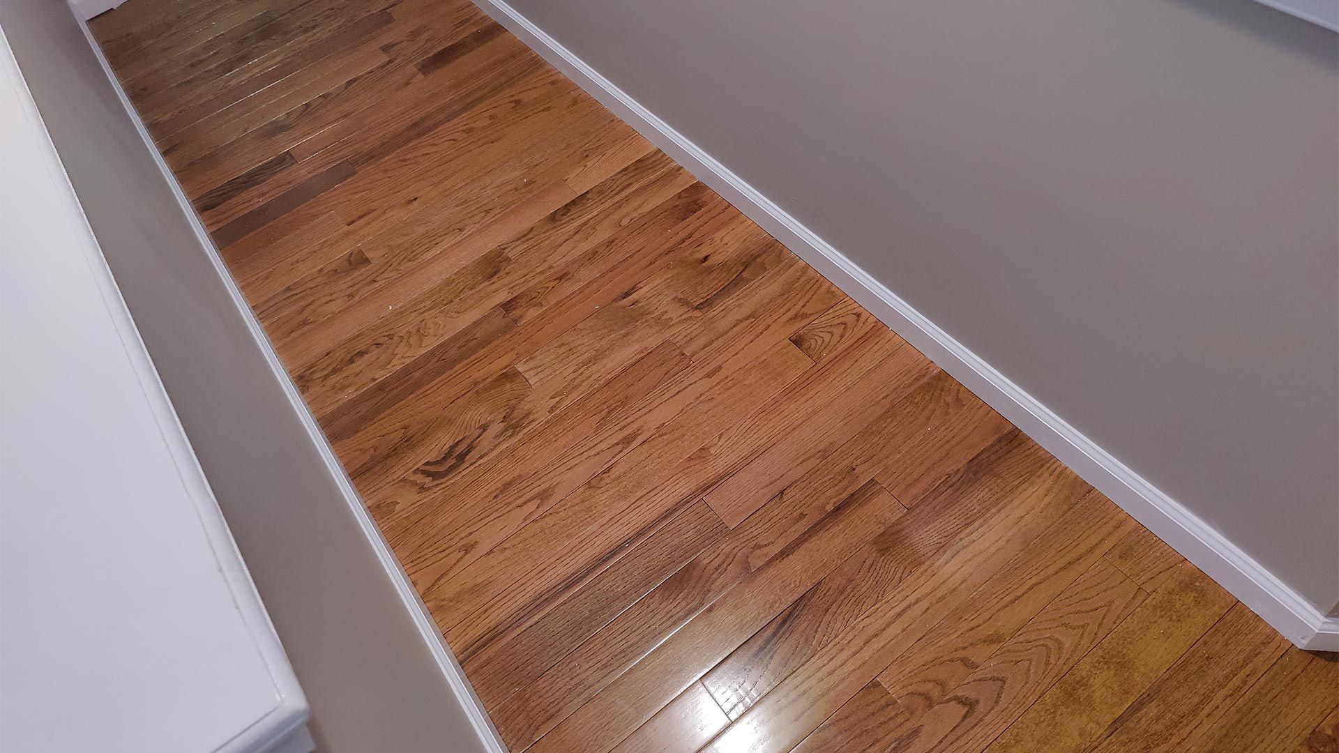 A hallway with hardwood floors and white trim in a house.
