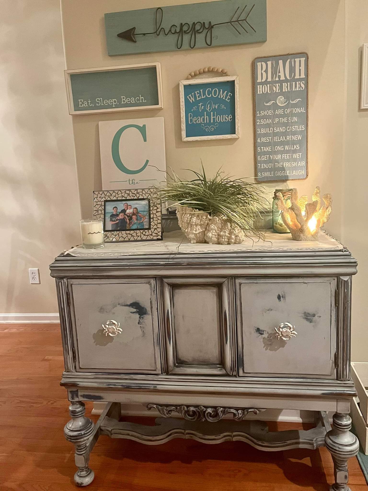 A dresser is sitting in a living room next to a wall with signs on it.