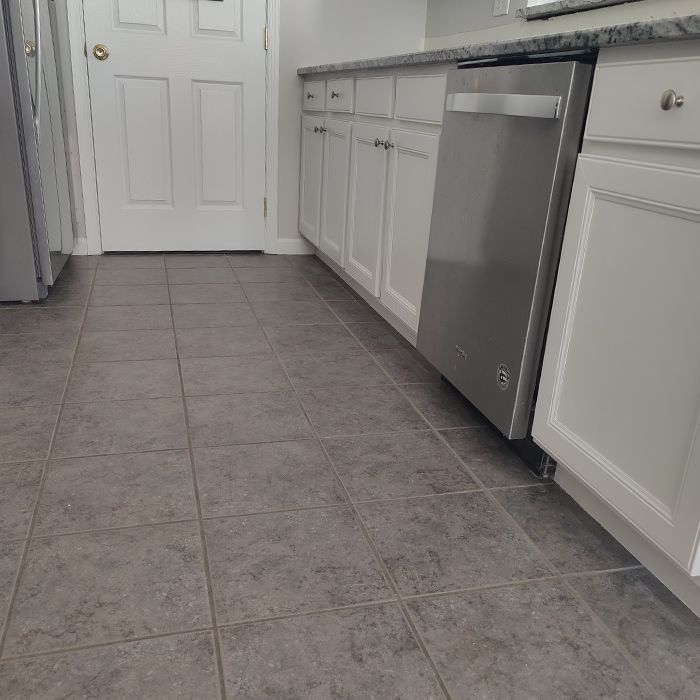 A kitchen with white cabinets and a stainless steel dishwasher