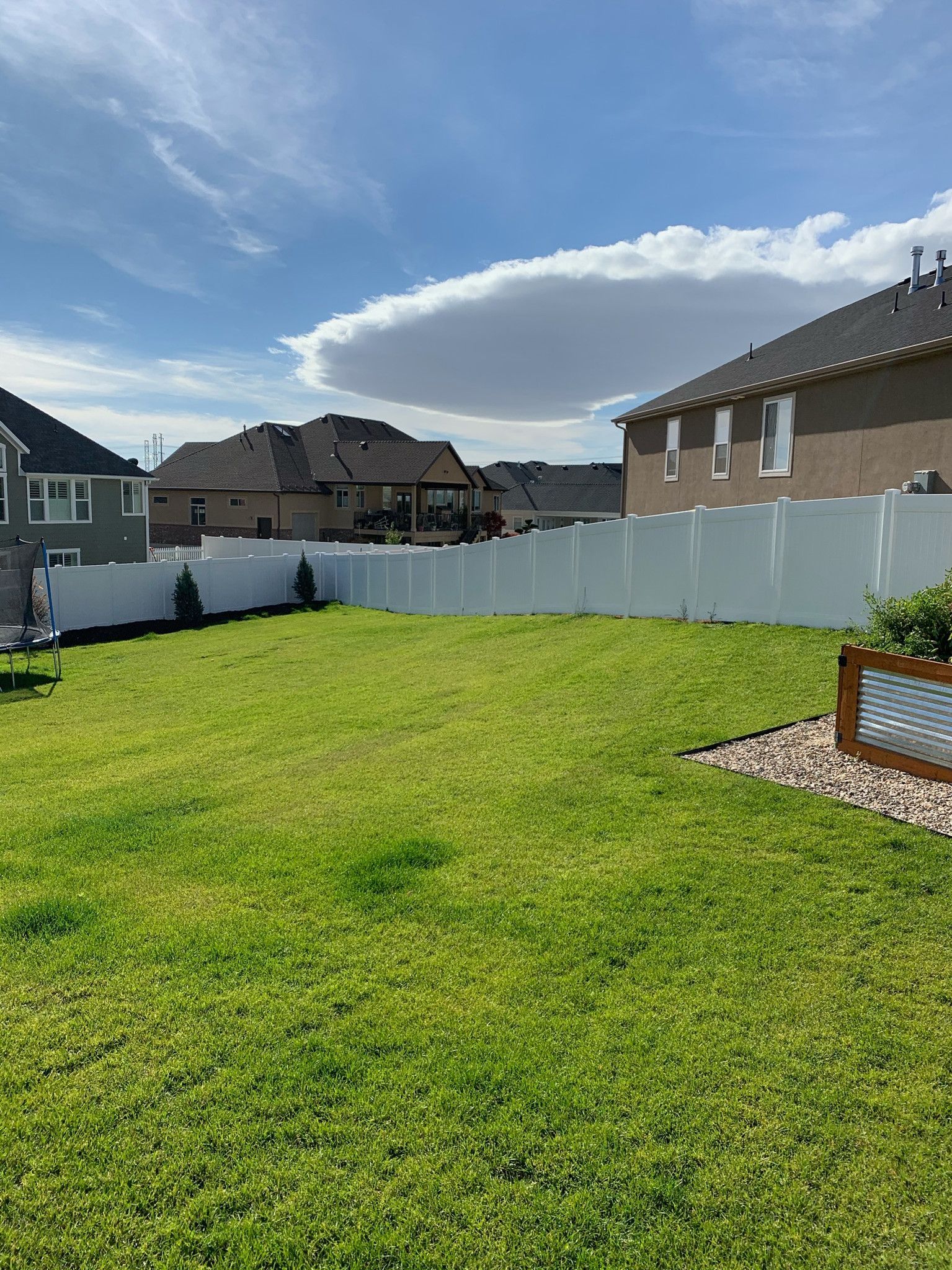 A backyard with a white fence and a lot of grass.