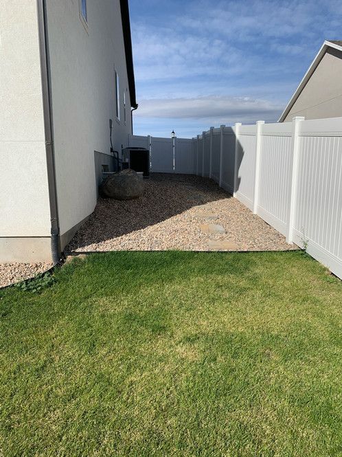 There is a white fence in the backyard of a house.