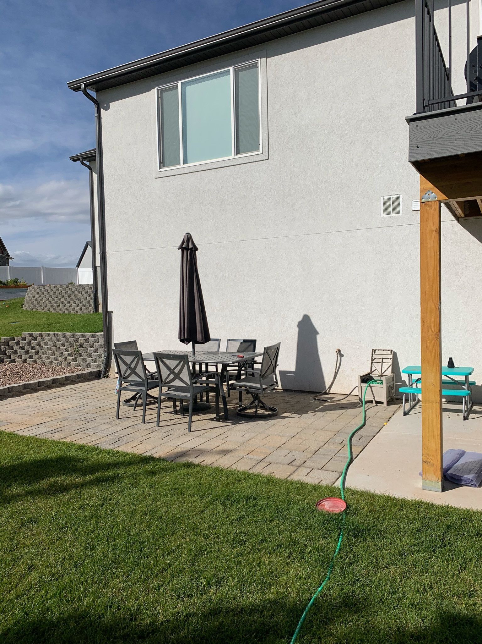 A backyard with a table and chairs and a hose