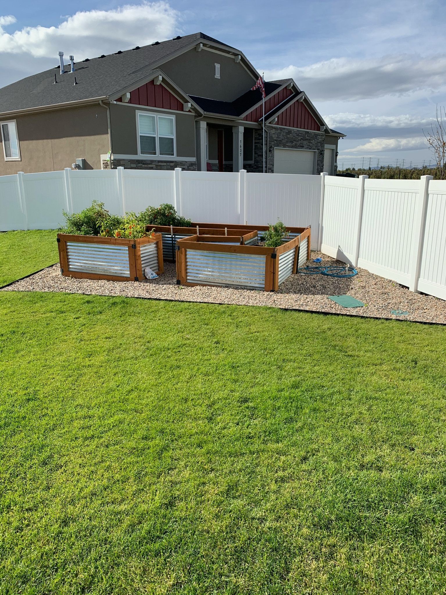 A backyard with a white fence and wooden planters in front of a house.