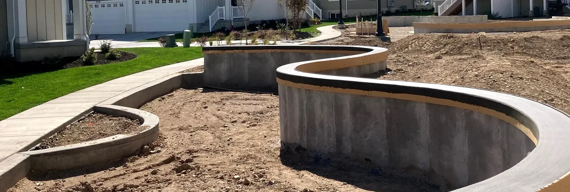 A concrete wall is being built in a yard next to a sidewalk.