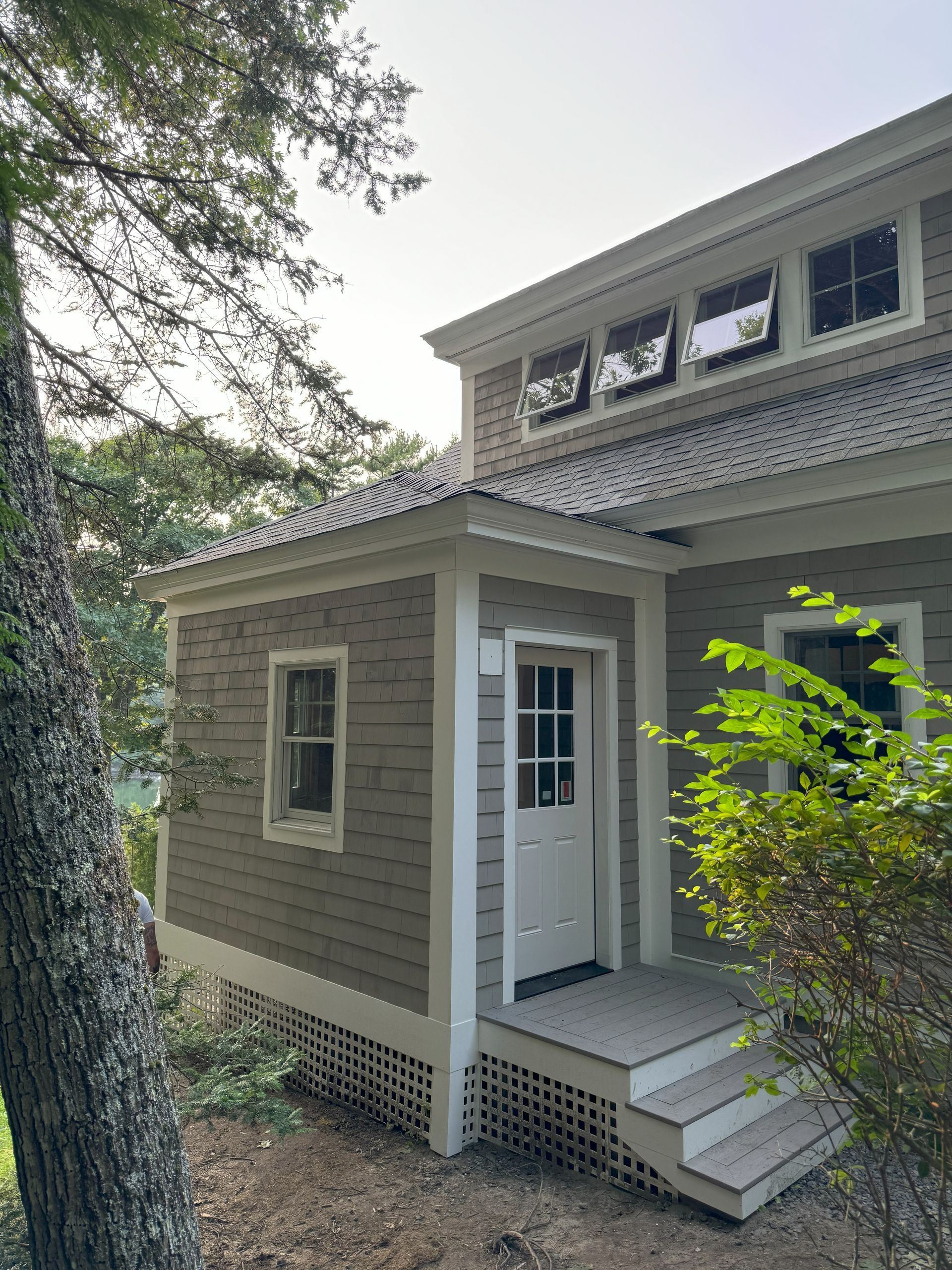 A house with a porch and stairs is surrounded by trees.