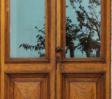 A wooden door with a tree reflection in the glass