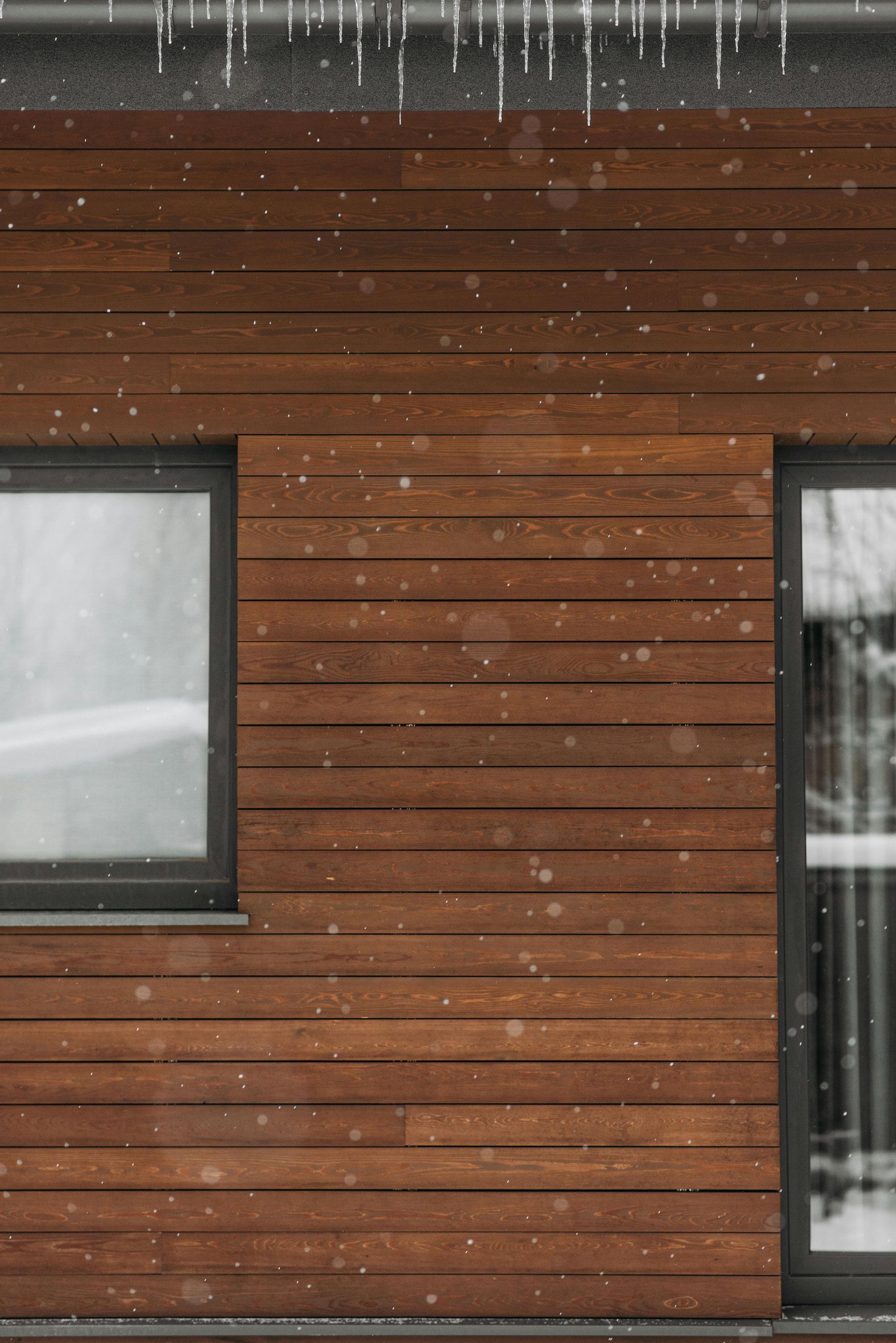 A wooden house with a window and icicles on the roof.