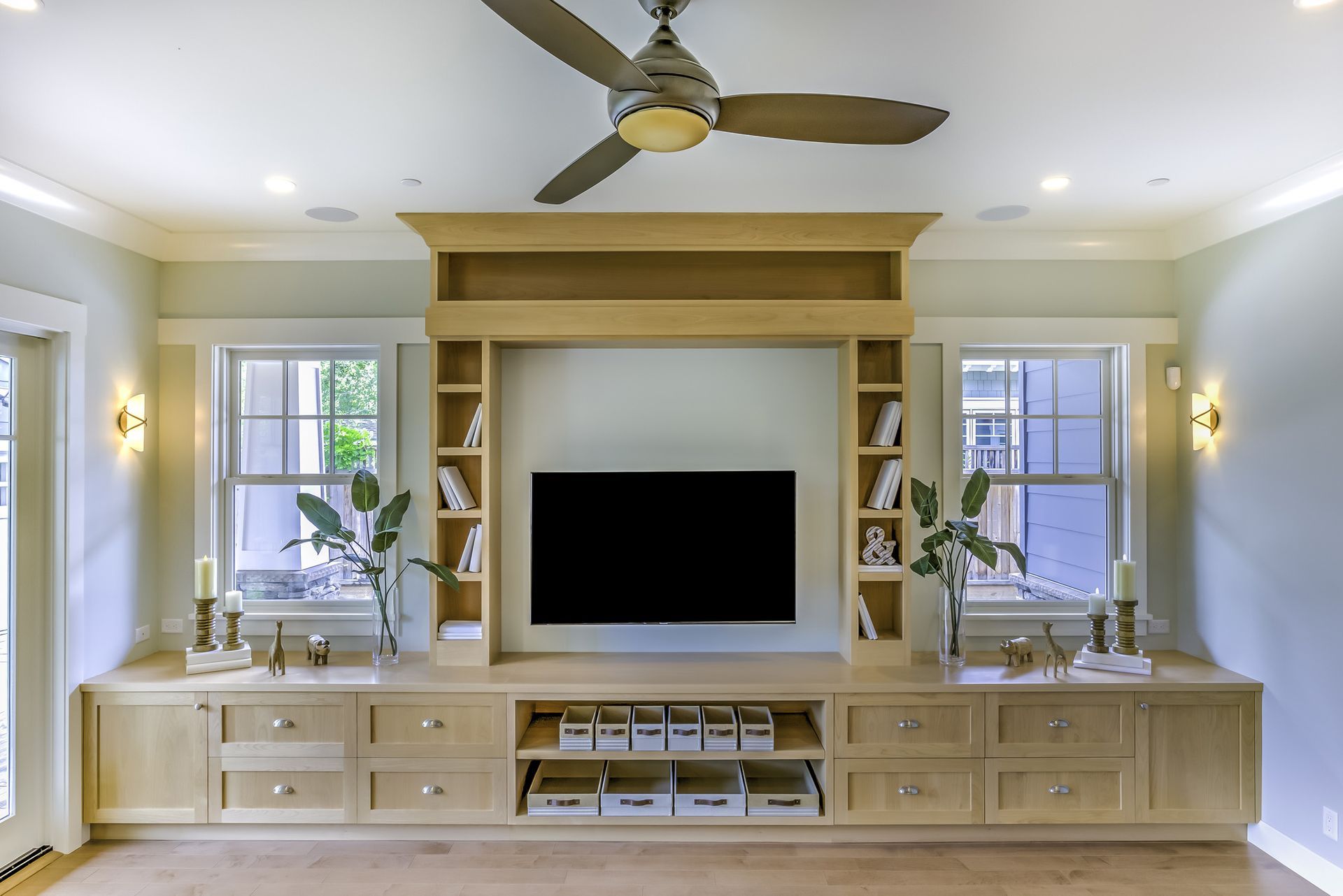 A living room with a flat screen tv and a ceiling fan.