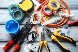 A bunch of electrical tools are sitting on a wooden table.