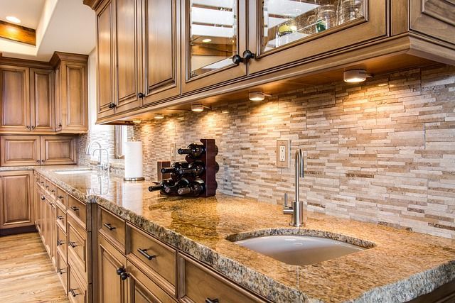 A kitchen with granite counter tops , wooden cabinets , and a sink.