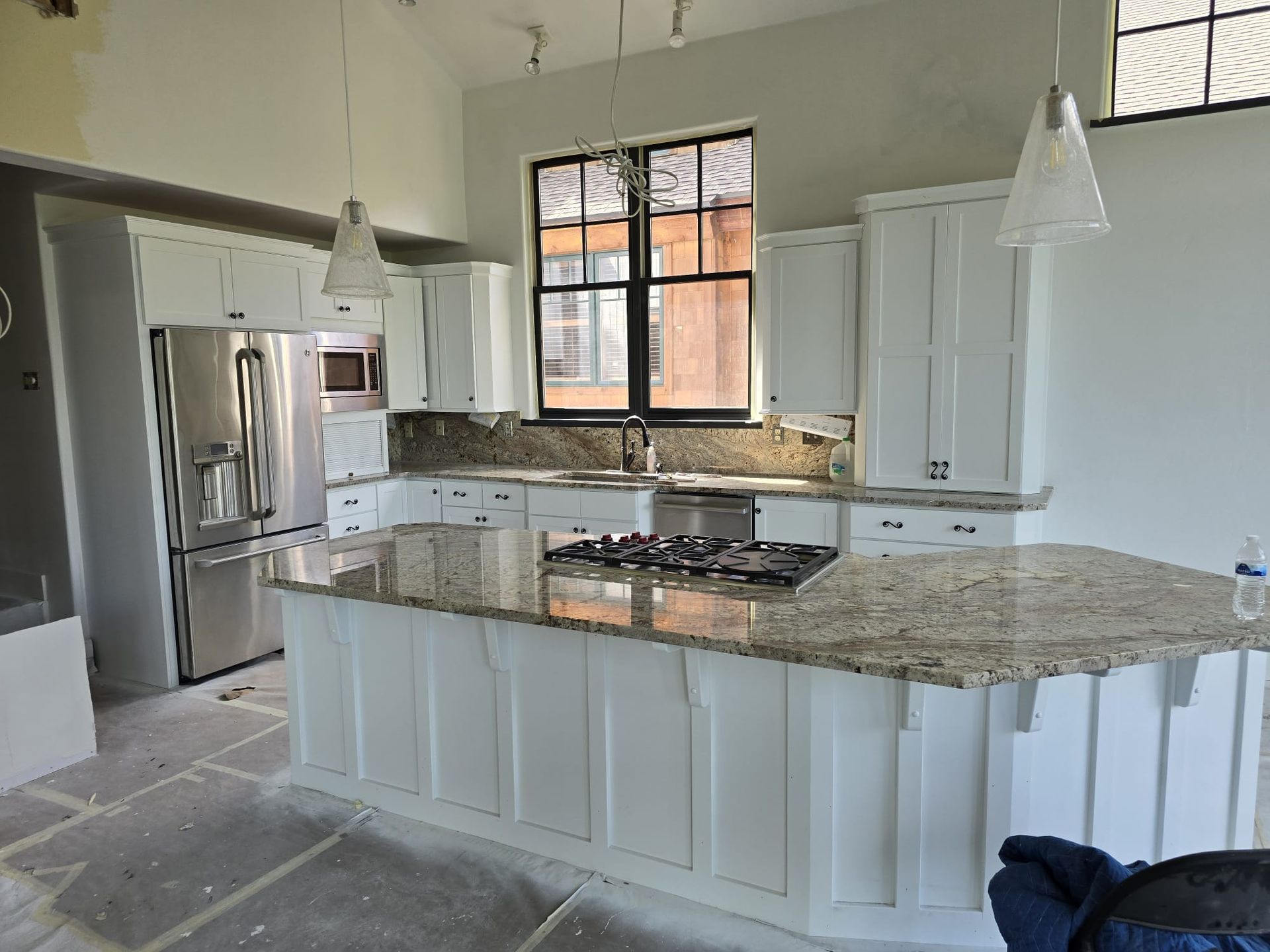 New kitchen remodel withe white cabinets and a large white island with light color granite countertops 