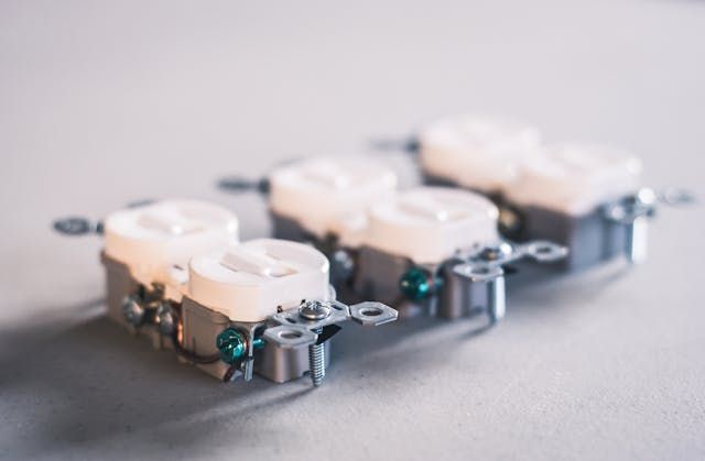 A row of white electrical outlets are sitting on a table.