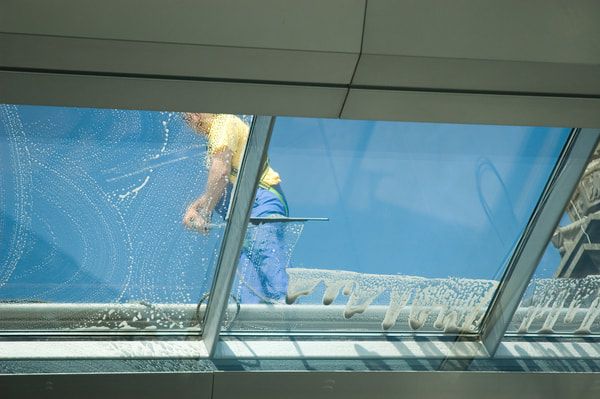 View from the inside of a home looking up at a professional cleaning a large skylight