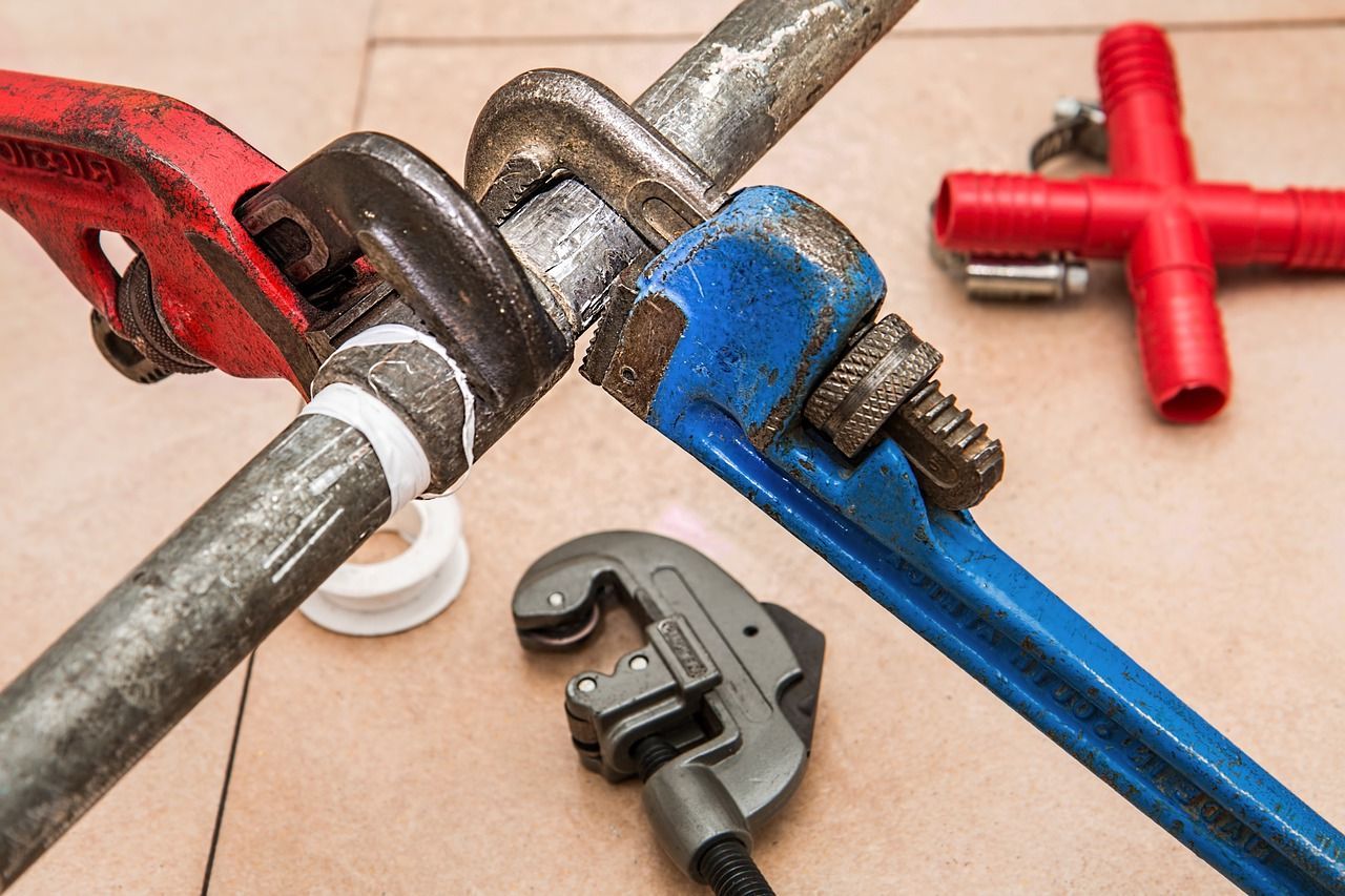 A couple of pipe wrenches tightening a pipe