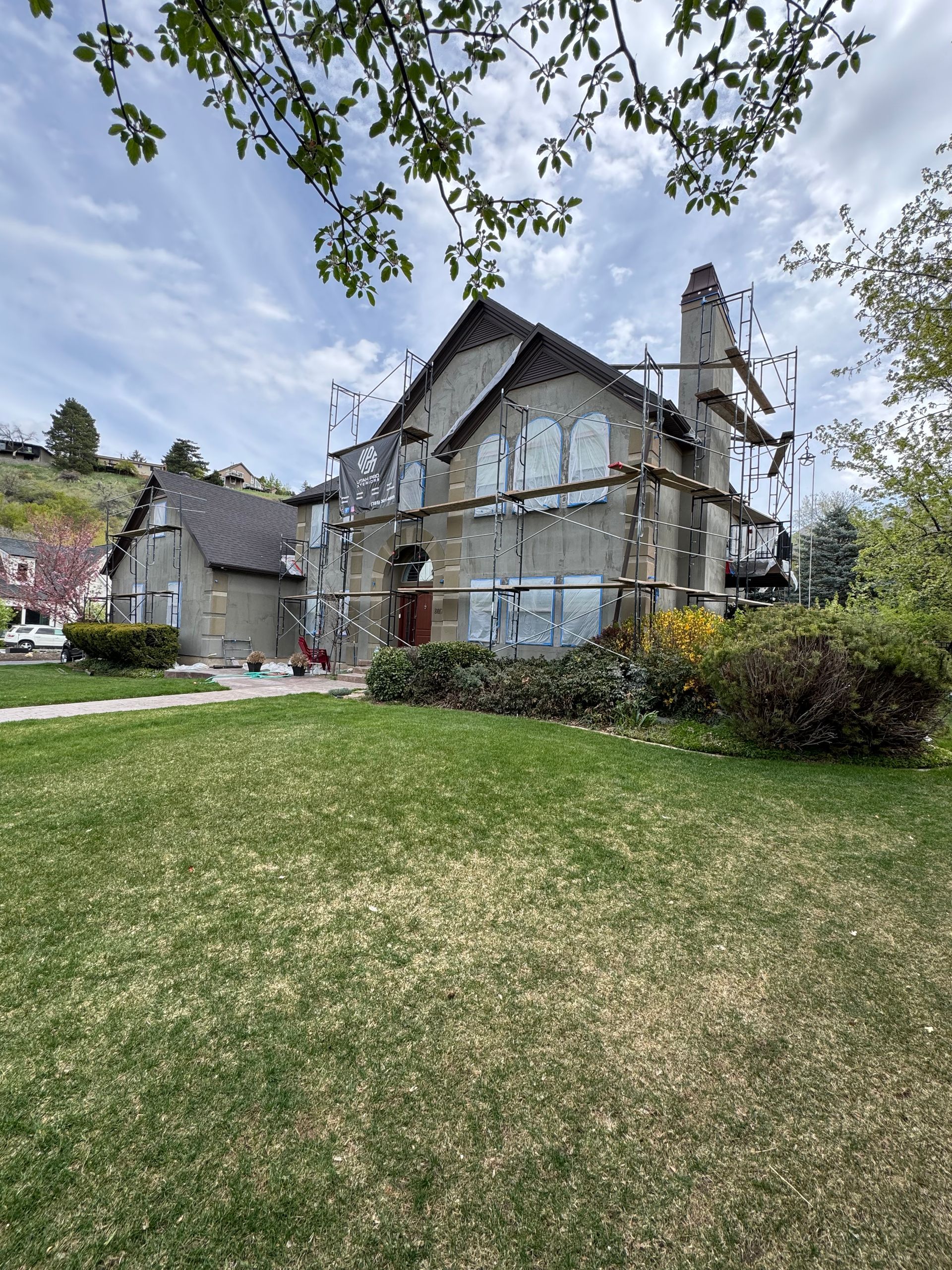 A large house with scaffolding around it is being painted.