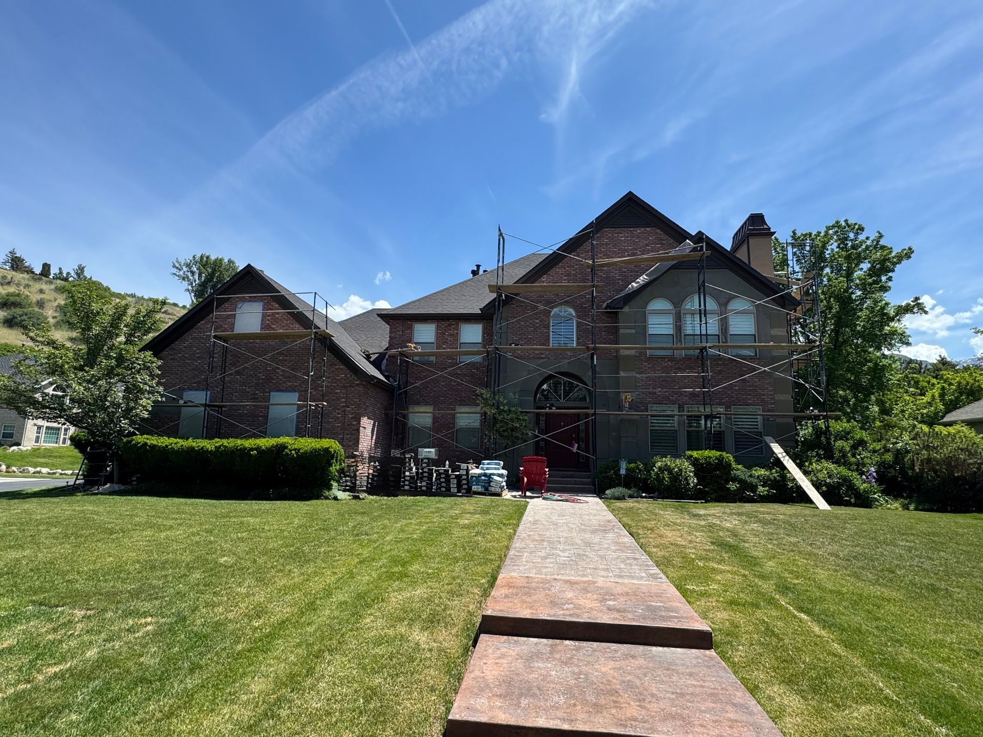 A large brick house with a lush green lawn and a walkway leading to it.